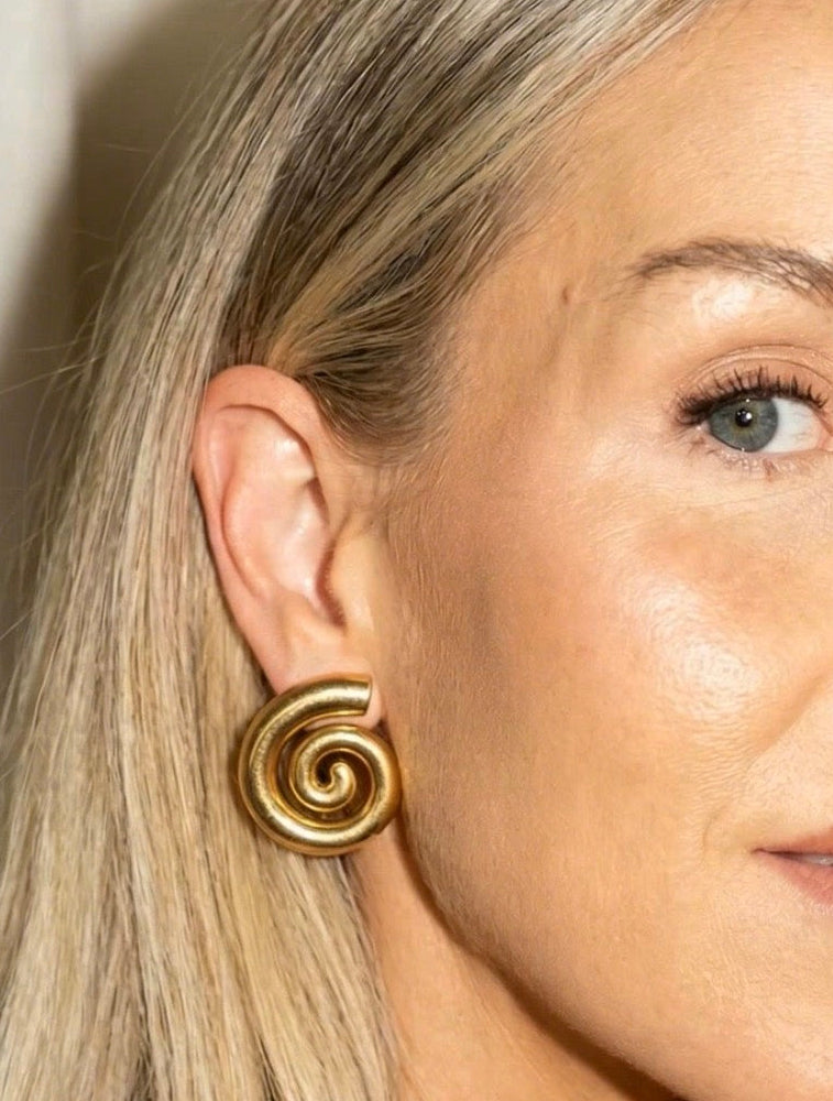 Close-up of a woman wearing a gold spiral earring.