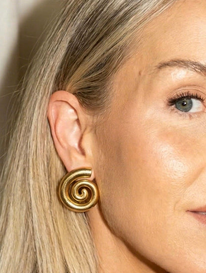 Close-up of a woman wearing a gold spiral earring.